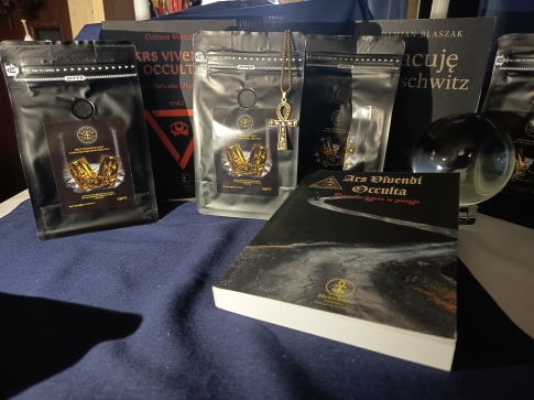 MysticRoots Coffee Caffè del Banchetto 250 g w aranżacji z książkami MysticRoots Publishing, złotym symbolem ankh i kryształową kulą.