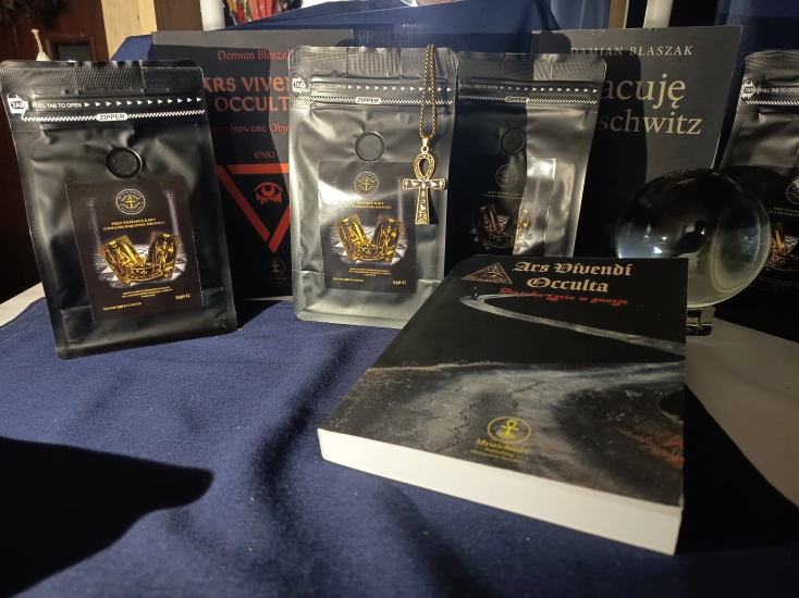 MysticRoots Coffee Caffè del Banchetto 250 g w aranżacji z książkami MysticRoots Publishing, złotym symbolem ankh i kryształową kulą.